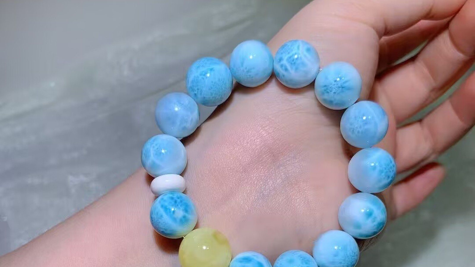 Natural larimar bead bracelet with sky-blue and white patterns worn on a wrist