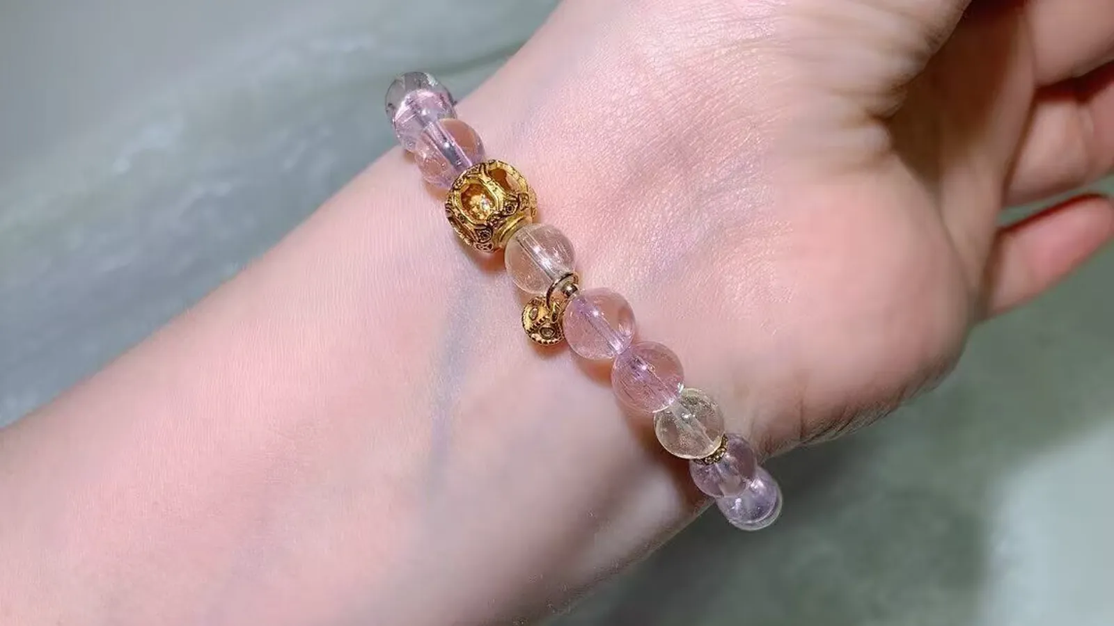 Cat's eye kunzite bracelet on a wrist: pale pink to lilac beads with vintage-style accents