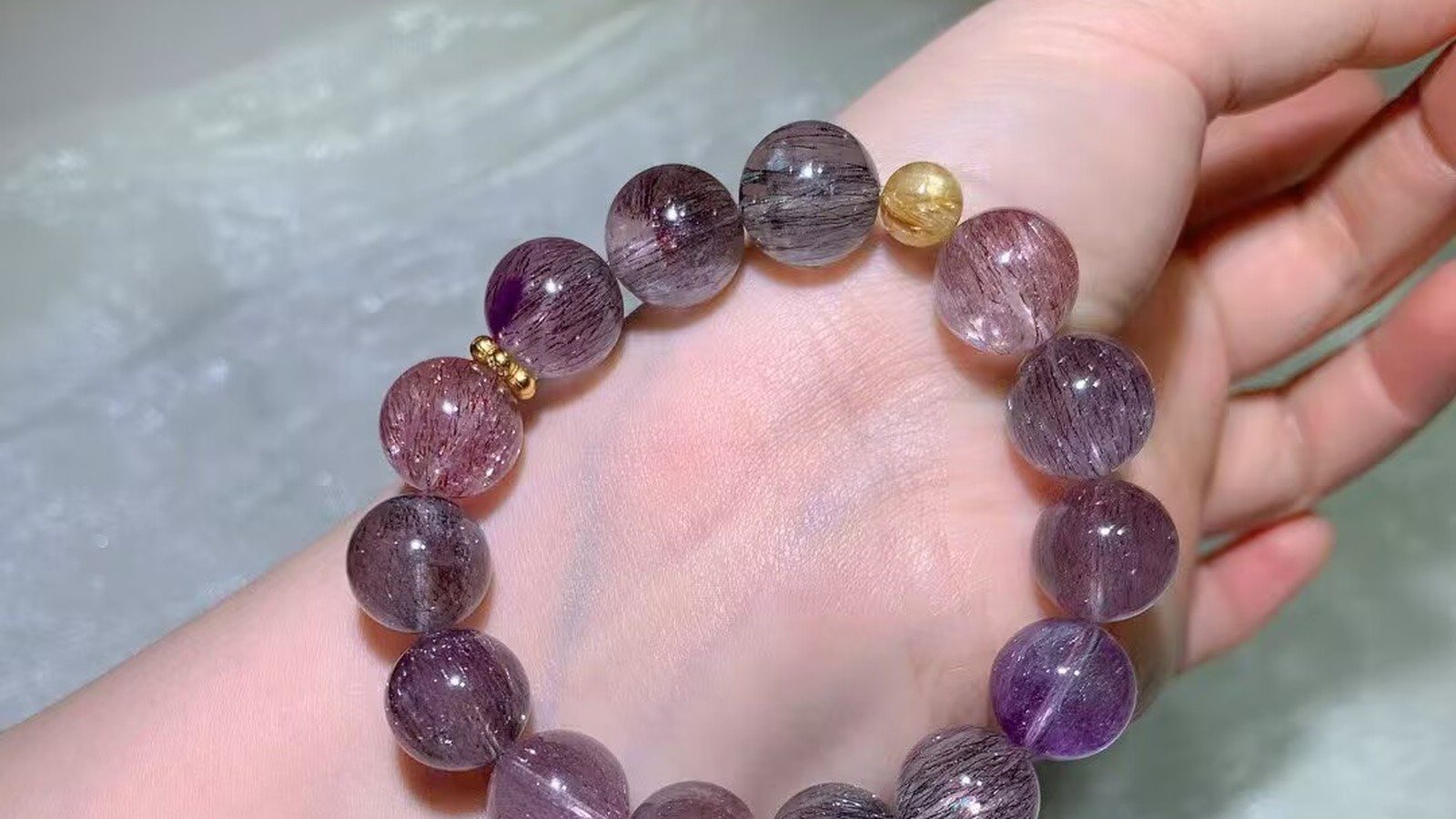 Natural Super Seven crystal bead bracelet with violet and smoky inclusions worn on a wrist