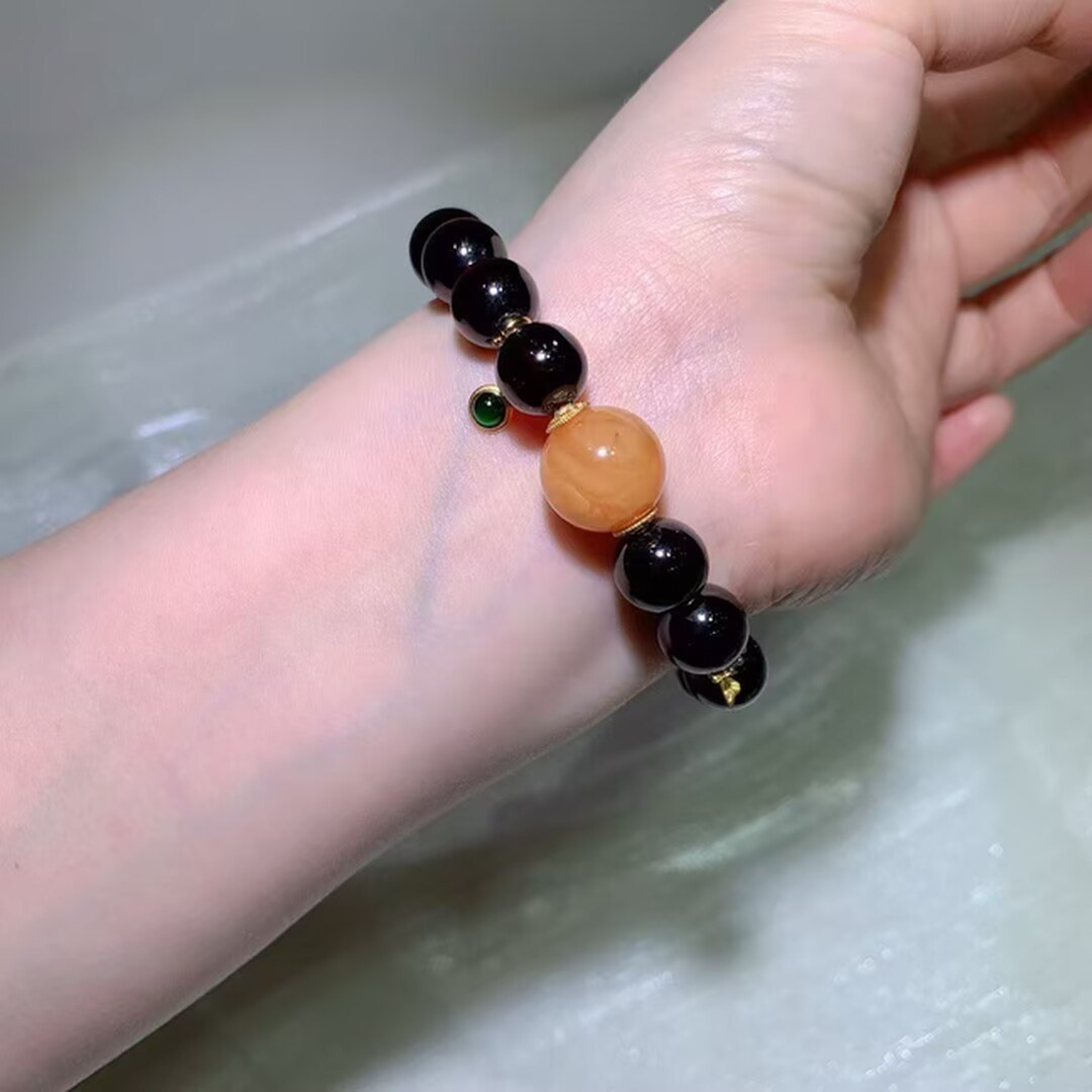 Wine-red garnet beads glowing in the light with a honey-colored accent bead