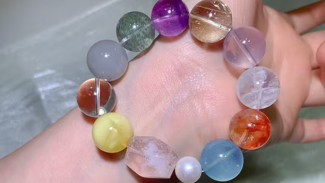 Natural multi-gem crystal bracelet with large beads in orange, green, honey, violet, pink and blue, worn on a wrist