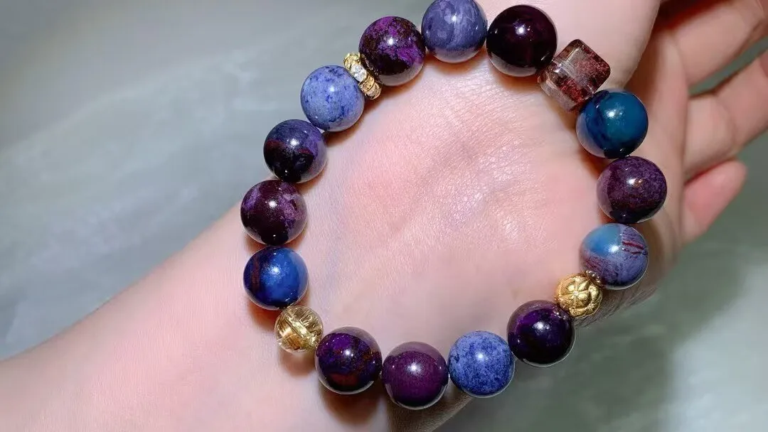 Sugilite bracelet on a wrist: plum-purple, deep violet and blue beads with golden rutile and vintage-style accents