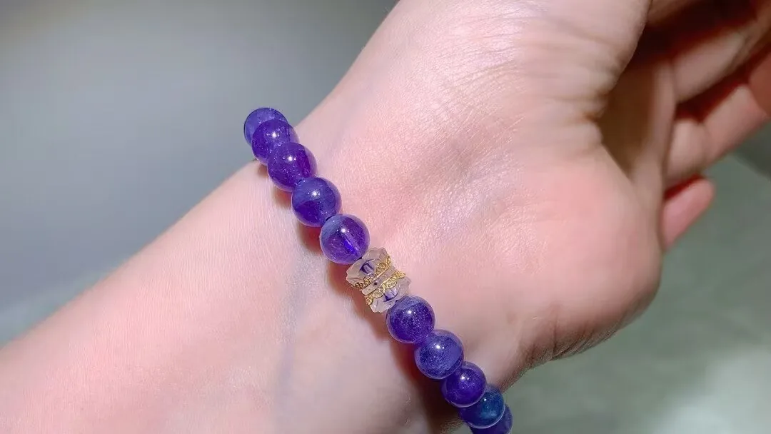 Violet-blue tanzanite bracelet on a wrist with vintage-style barrel beads